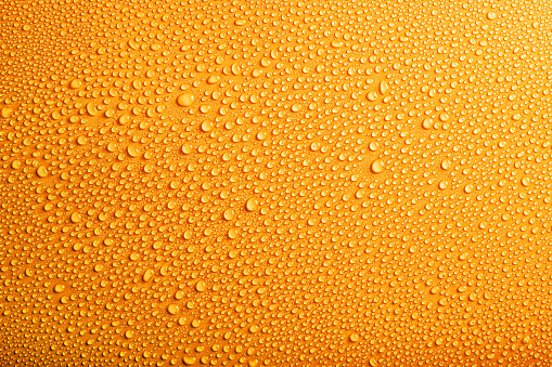 Pattern of small water drops on yellow background. Top view