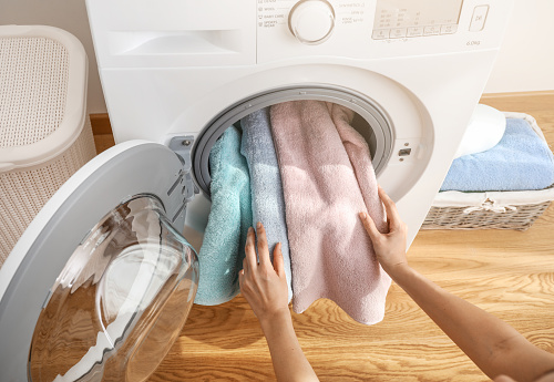 Person loading bath towels in washing machine