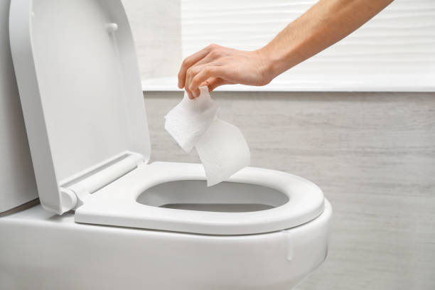 istock Hand throwing out toilet sheet in bowl 1218082468