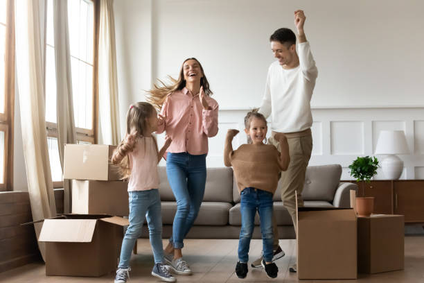 istock Overjoyed young couple having fun with daughters in new apartment. 1218085175