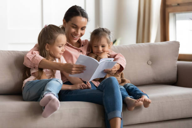 istock Happy young mixed race babysitter reading book to children. 1218085190