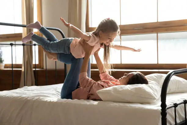 Photo of Healthy young mixed race mother lifting small preschool daughter.