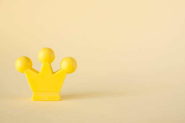 Miniature yellow crown on a beige background. Championship Symbol.