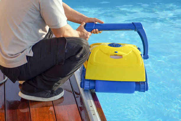 istock Hotel staff worker cleaning the pool. A pool cleaner holds a robot cleaner. 1218090847