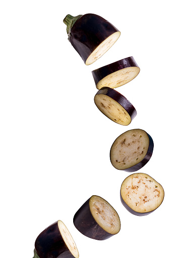 Flying vegetables. Falling sliced eggplant isolated on white background to use in design.