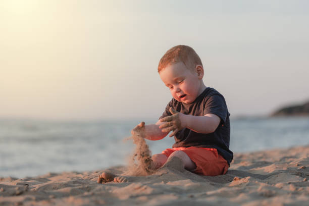 istock Little boy playing sand alone at the beach 1218091585