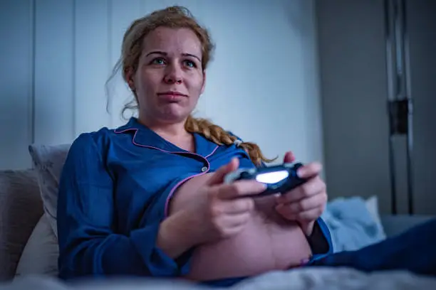 Happy pregnant woman playing video games.