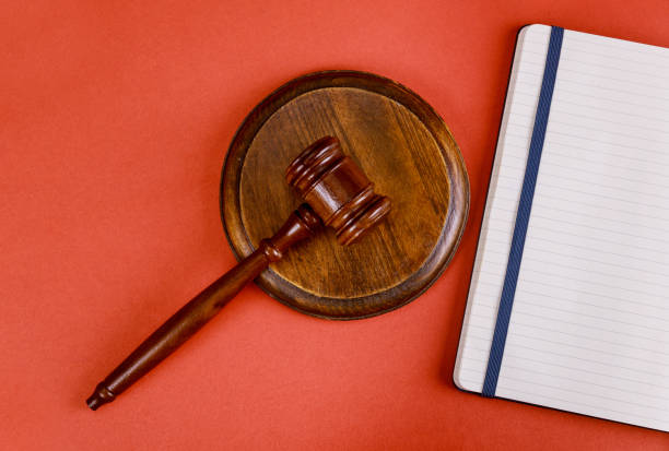 istock Workspace for lawyer with judge gavel in lawyer notepad on a red table 1218097695