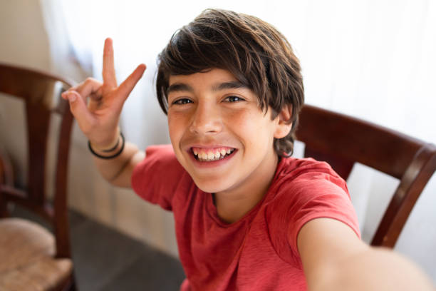 lindo latinx hispano niño sonriendo mientras se toma selfie en casa - brown eyes fotografías e imágenes de stock