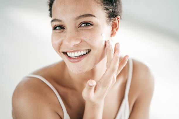 istock Smiling young women applying moisturiser to her face 1218104290
