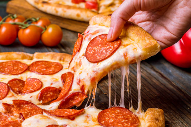 hand takes pizza hand takes pizza salami stock pictures, royalty-free photos & images