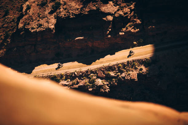 Motorcycle off roading in Moab Utah Looking down from a cliff at two off road motorcycle riders near Moab Utah camel colored photos stock pictures, royalty-free photos & images