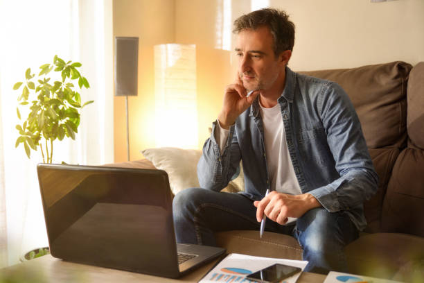 istock Man working at home on a sofa looking at laptop 1218110621