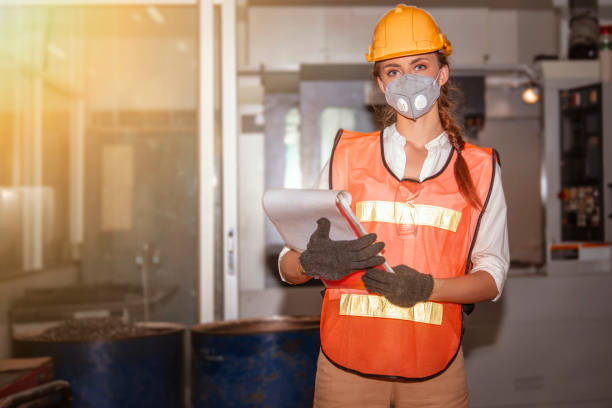 Young woman engineer in the mask on protected herself with air pollution & virus Young woman engineer in the mask protected herself with air pollution & virus with controller machine on blurred factory background safety first at work stock pictures, royalty-free photos & images