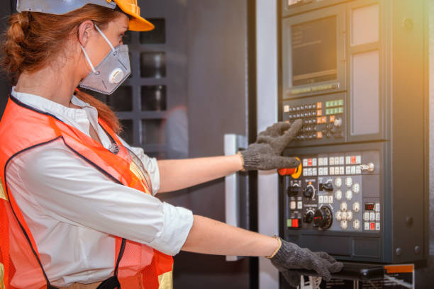 Young woman engineer in the mask protected herself with air pollution & virus with controller machine on blurred factory background stock photo