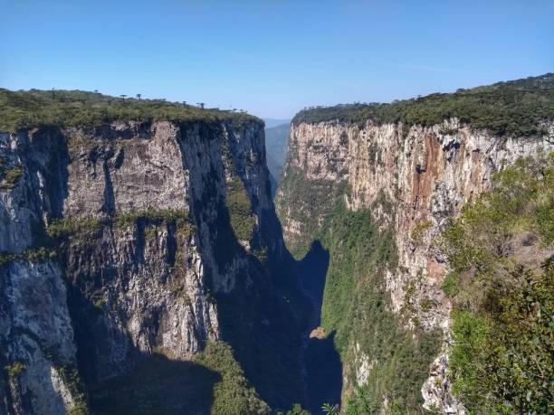 Itaimbezinho Canyon - Serra National Park Parades - Canyons Aparados da Serra National Park is in south Brazil, near the Atlantic coast. It’s known for the deep, dramatic Fortaleza and Itaimbezinho Canyon, two of many chasms that cut through the park’s plateaus. Footpaths, like the Rio do Boi trail, pass waterfalls and make a steep, rocky descent to the canyon floor. The lush landscape is home to howler monkeys, ocelots, parrots and other rare wildlife. The town Cambará do Sul is nearby. canyon itaimbezinho rio grande do sul santa catarina southern brazil stock pictures, royalty-free photos & images