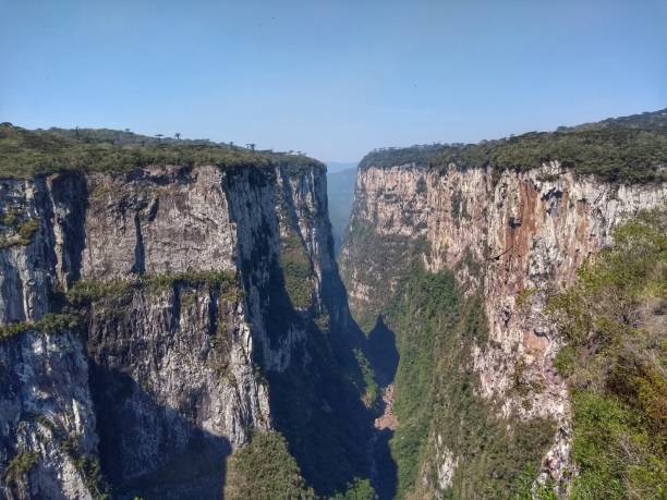 Itaimbezinho Canyon - Serra National Park Parades - Canyons Aparados da Serra National Park is in south Brazil, near the Atlantic coast. It’s known for the deep, dramatic Fortaleza and Itaimbezinho Canyon, two of many chasms that cut through the park’s plateaus. Footpaths, like the Rio do Boi trail, pass waterfalls and make a steep, rocky descent to the canyon floor. The lush landscape is home to howler monkeys, ocelots, parrots and other rare wildlife. The town Cambará do Sul is nearby. canyon itaimbezinho rio grande do sul santa catarina southern brazil stock pictures, royalty-free photos & images