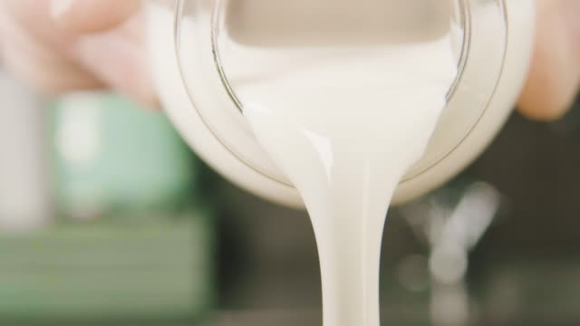 Cream being poured from a miniature milk bottle