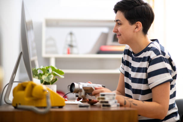 Young Woman Working From Home at her Video Editing Job Woman edits home movies in her home office during the coronavirus pandemic. female film editor stock pictures, royalty-free photos & images