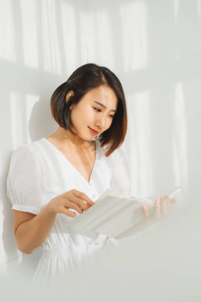 istock Young woman reading a book while relaxing at home with sunlight. 1218125702