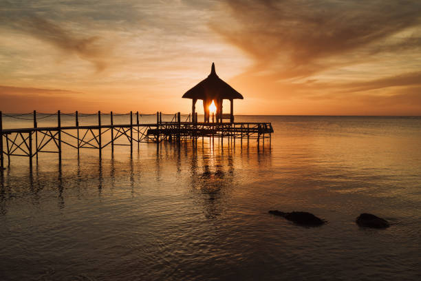 Mauritius Beach Sunset. Colorful sunset at the beach, sun shining through wooden jetty pavillion over Indian Ocean. North West Coast of Mauritius Island, East Africa