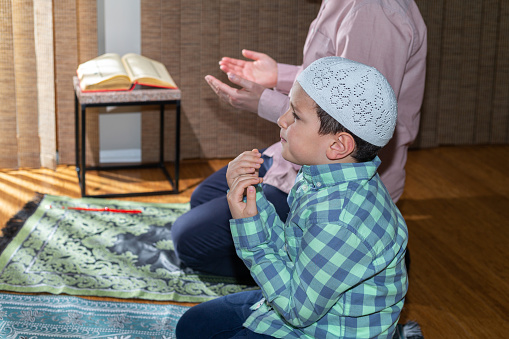 Muslim boy learning how to make pray to Allah in ramadan