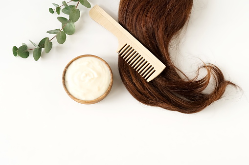pelo femenino, máscara de pelo y peine de bambú en la vista superior de fondo blanco, plana. espacio de copia. Concepto de autocuidado. photo