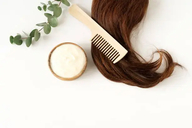 Photo of female hair, hair mask and bamboo comb on white background top view, flat lay. copy space. Self care concept.