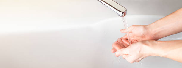 lavabonun üzerinde banyoda bir su deresi altında el yıkama. panoramik afiş arka plan. hijyen konsepti. coronavirus, covid-19 - su kesintisi stok fotoğraflar ve resimler