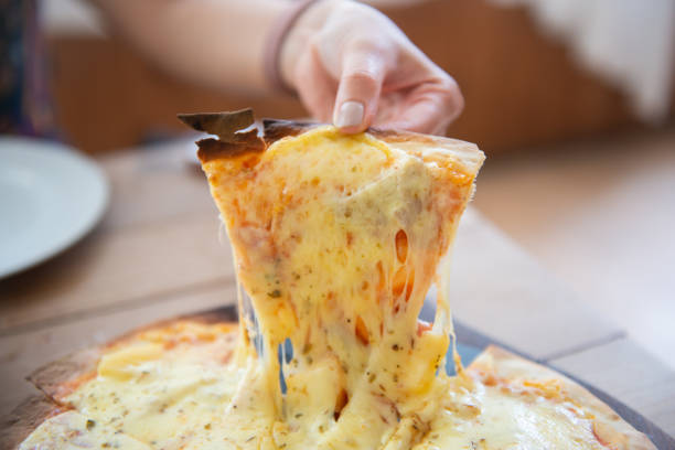 istock Human hand is pick up pizza with stretched cheese from the pizza tray 1218137907