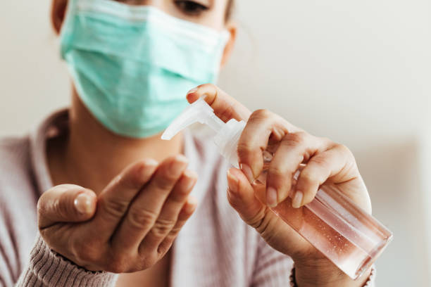 Close-up of woman cleaning her hands with antiseptic hand gel. Close-up of woman using antibacterial hand gel at home. state of emergency stock pictures, royalty-free photos & images