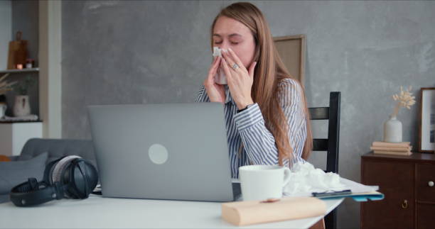 istock Beautiful young Caucasian blonde woman is sick with cold, sneezing while using laptop to work from home on quarantine. 1218148955