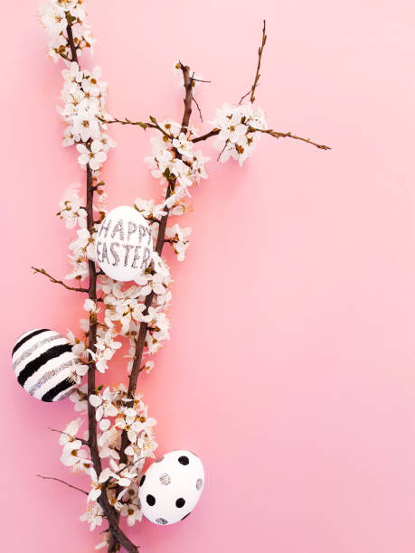 istock Composition of spring flowers, blooming tree branches and eggs with black, silver lines and polka dots on a pink background. Glitter inscription Happy Easter. Flat lay, top view, close up, copy space 1218149477