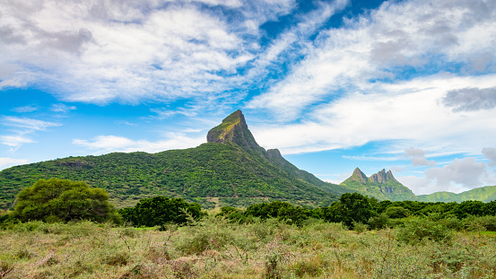 Panorama view to Montagne du Rempart - Mount Rempart Peak with the Trois Mamelles Mountain Peaks on the right horizon under blue summer sky. Montagne du Rempart, Black River District, Mauritius, East Africa