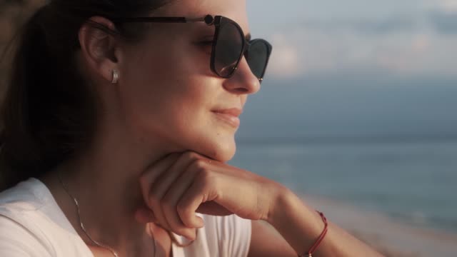 Beautiful young woman in sunglasses watching sky and sunset.