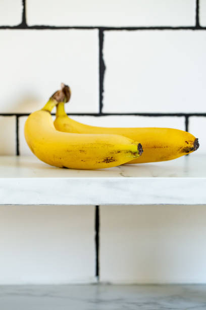 Two ripe yellow bananas on white marble background