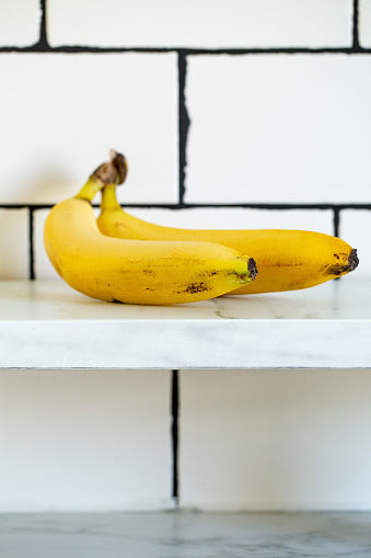 Two ripe yellow bananas on white marble background