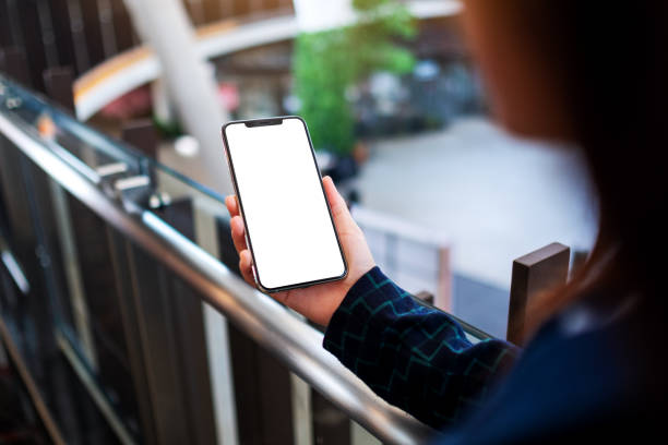 istock a woman holding mobile phone with blank white screen indoors 1218154846
