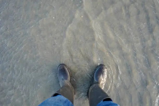 Welly boots standing in sand and water on a beach
