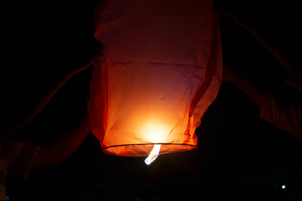 istock Person holding a red sky lantern with the flames showing clearly 1218165393