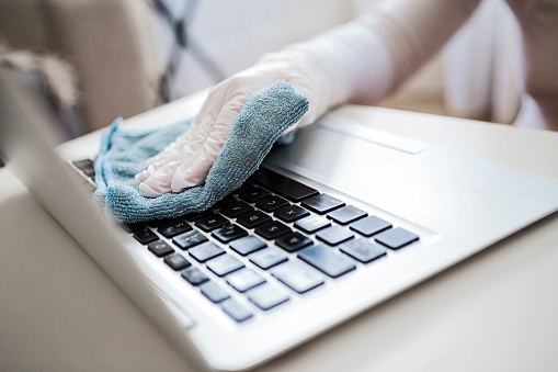 Woman disinfects the laptop keyboard
