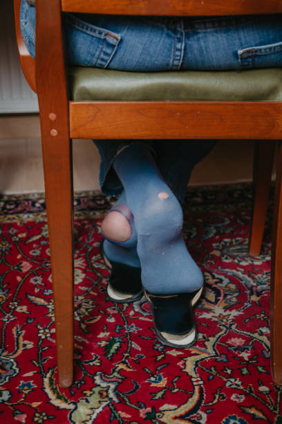 istock Man sits on chair on his socks can see holes 1218170484