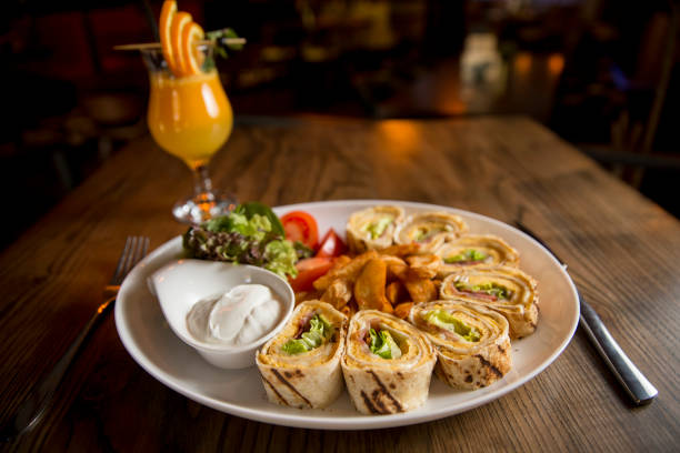 Freshly made omelette rolls in the plate on the table with orange juice
