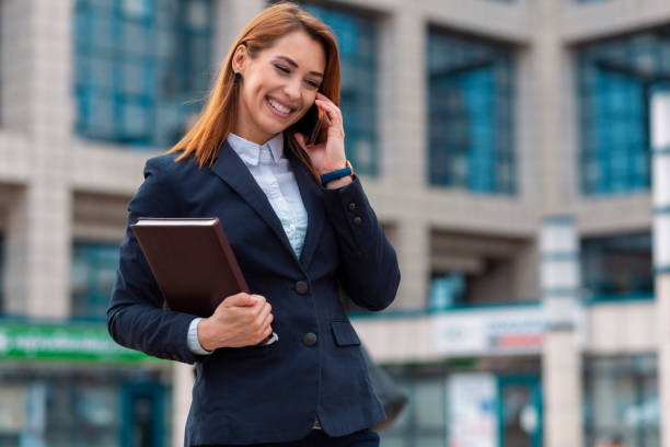 beautiful business woman talking on phone outdoor - lawyer young adult suit expressing positivity imagens e fotografias de stock