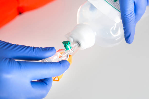 istock First Aid. Preparing an IV drip. Inserting the spike into the port, without touching the end 1218171866