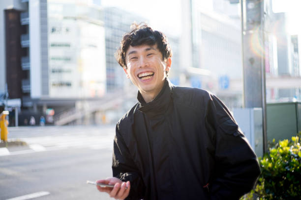 明るいバックライトで笑顔で立っている日本人男性の肖像 - 笑う ストックフォトと画像