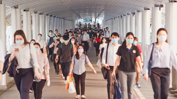 Less crowded Asian people wear face mask walk in pedestrian walkway. Coronavirus disease Covid-19 pandemic outbreak concept stock photo