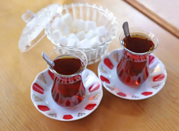 Photo of traditional turkish tea with sugar cubes on wooden table