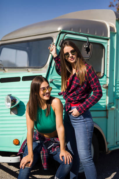 istock Smiling young women by the vintage minivan 1218174767