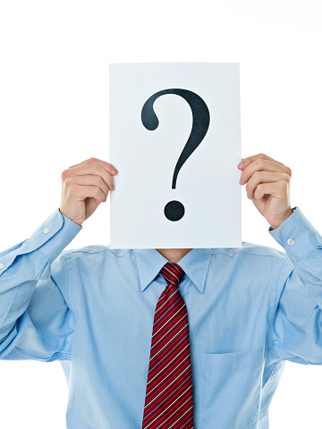 Confused businessman holding question mark against white background.